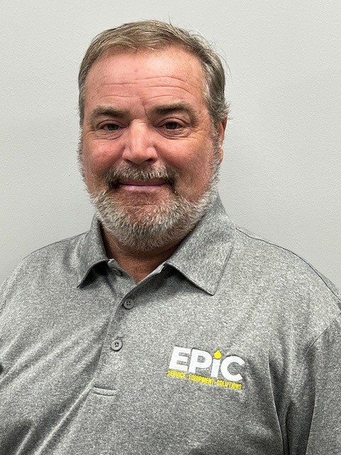 A man with short gray hair and a beard wears a gray polo shirt with an EPIC Service Equipment Solutions logo, standing against a plain light-colored background.